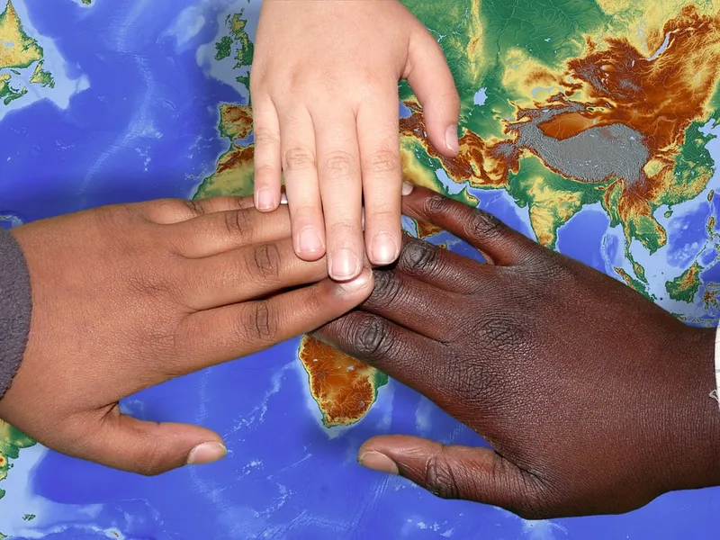 Mãos unidas sobre um mapa-múndi, representando apoio e conexão entre países