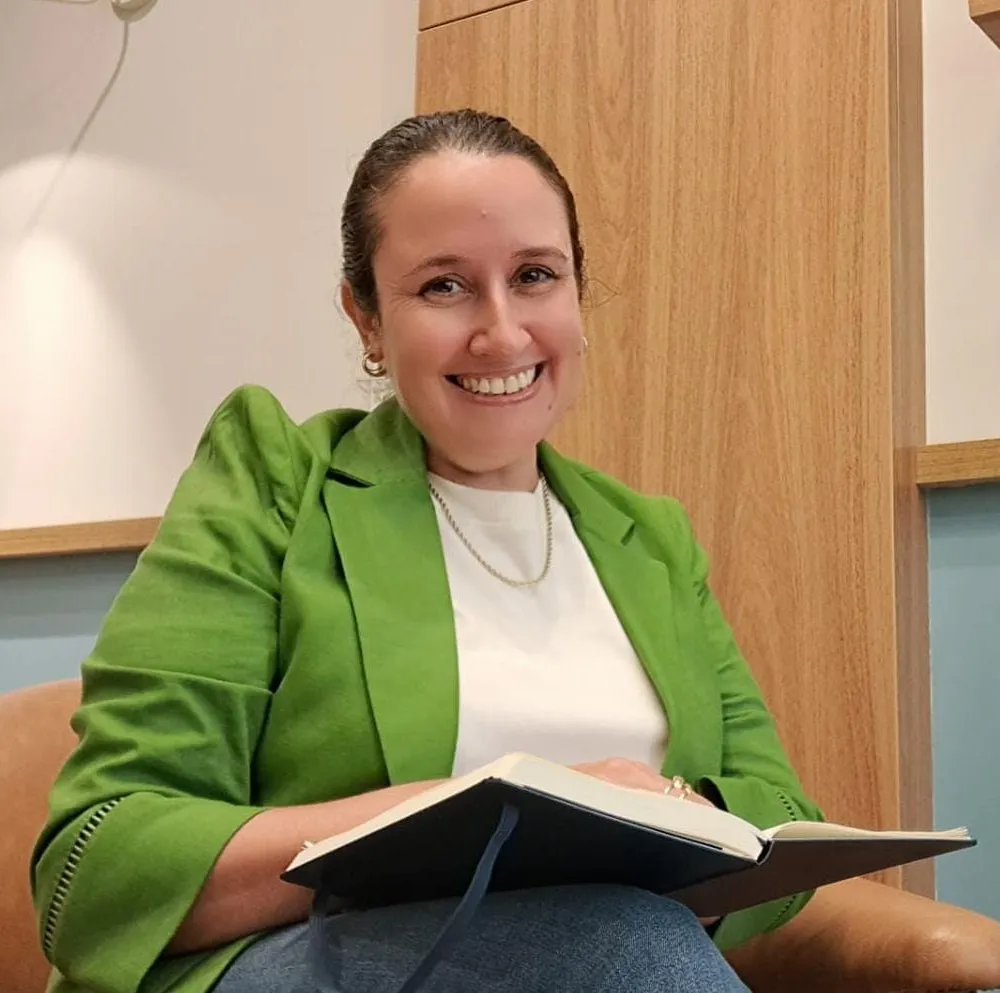 Ana Sousa, psicóloga clínica, sentada no consultório com um livro no colo